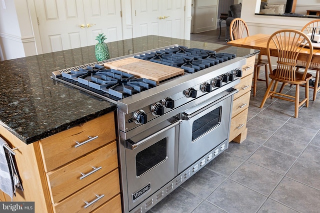 kitchen with dark stone counters, dark tile patterned flooring, and range with two ovens