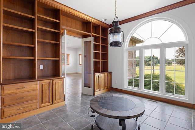 interior space with french doors, dark tile patterned floors, and ornamental molding