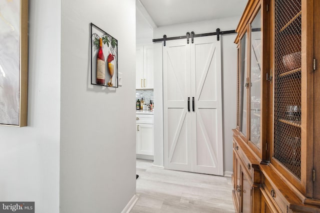 corridor featuring a barn door and light hardwood / wood-style flooring