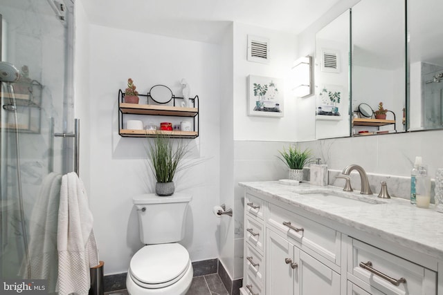 bathroom with tile patterned flooring, vanity, toilet, and walk in shower