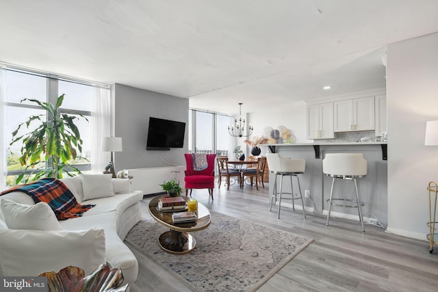 living room featuring a healthy amount of sunlight, light hardwood / wood-style flooring, and a chandelier