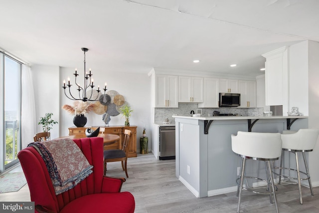 kitchen featuring white cabinets, kitchen peninsula, an inviting chandelier, and a kitchen breakfast bar