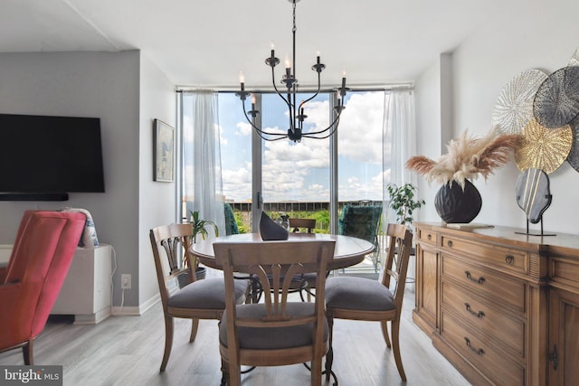 dining area with light wood-type flooring, expansive windows, and an inviting chandelier