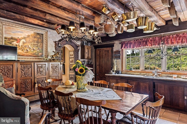 dining room featuring wooden ceiling, light tile patterned floors, sink, a notable chandelier, and beamed ceiling