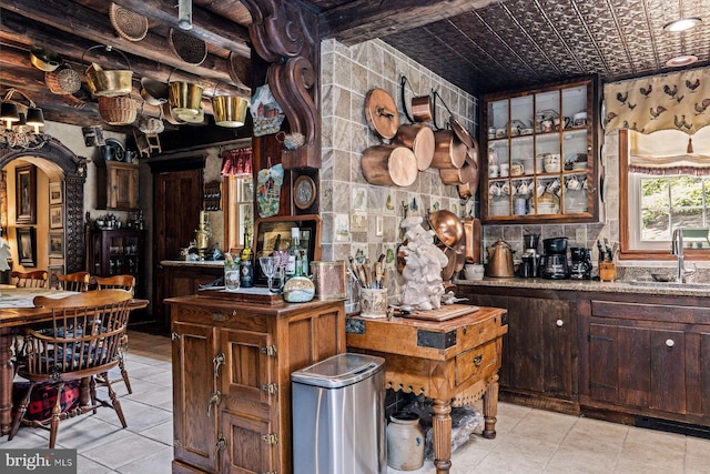 bar with light tile patterned floors, sink, and dark brown cabinets