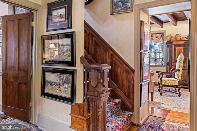 stairway with beamed ceiling and hardwood / wood-style flooring