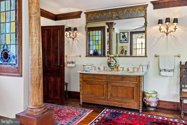 bathroom with vanity, crown molding, decorative columns, wood-type flooring, and ceiling fan