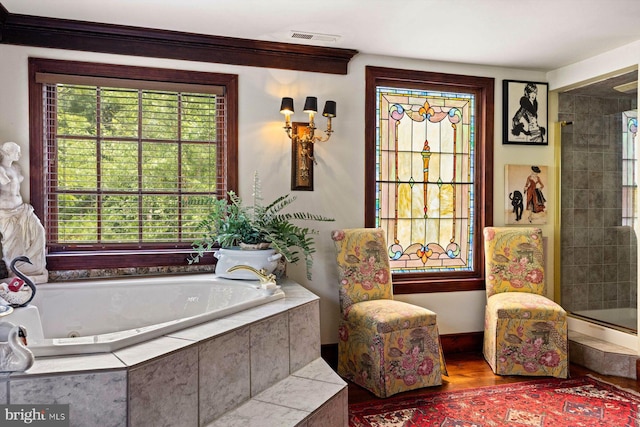 bathroom featuring plus walk in shower, plenty of natural light, and hardwood / wood-style flooring