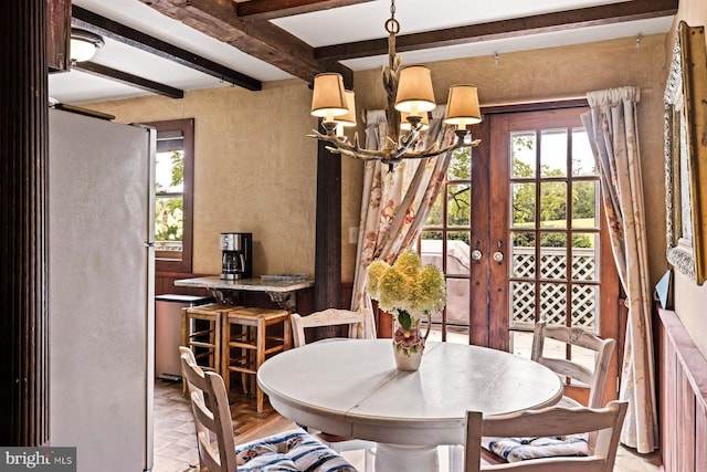 dining space with beamed ceiling and a chandelier