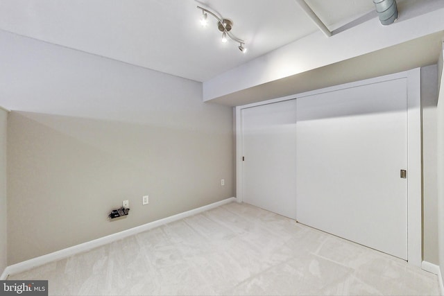 unfurnished bedroom featuring track lighting, light colored carpet, and a closet