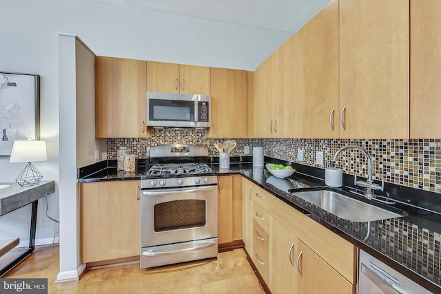 kitchen featuring light brown cabinetry, appliances with stainless steel finishes, dark stone counters, and sink