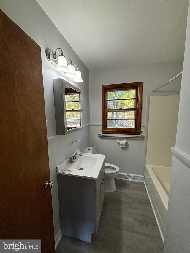 full bathroom with shower / bathing tub combination, vanity, wood-type flooring, and toilet