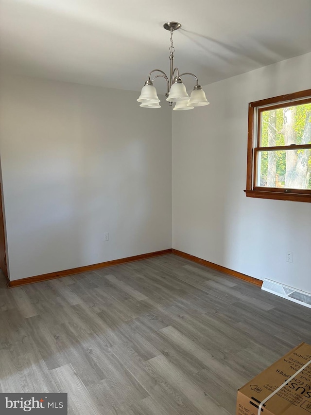 empty room with a chandelier and hardwood / wood-style flooring