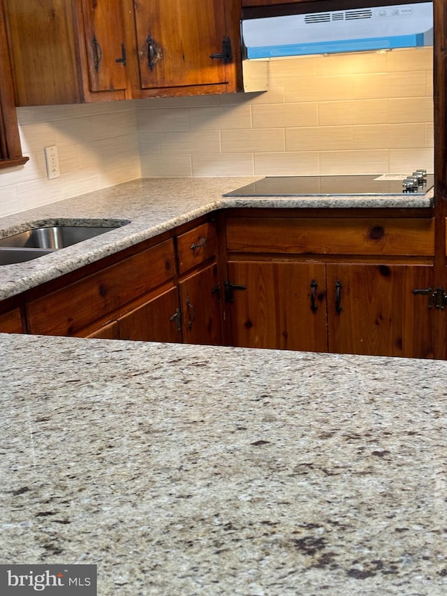 kitchen with black electric stovetop, tasteful backsplash, and ventilation hood