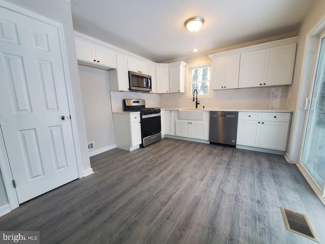 kitchen featuring white cabinets, sink, stainless steel appliances, and dark wood-type flooring