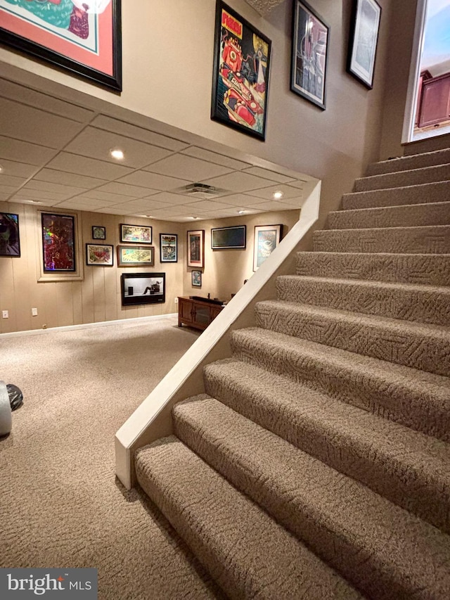 stairs featuring carpet flooring and a paneled ceiling