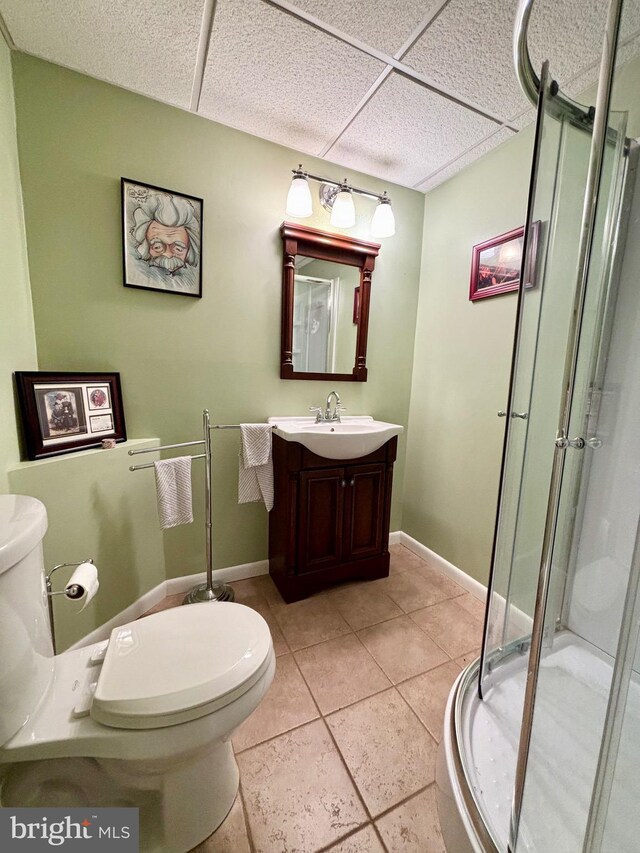 bathroom with vanity, tile patterned floors, a drop ceiling, toilet, and a shower with door