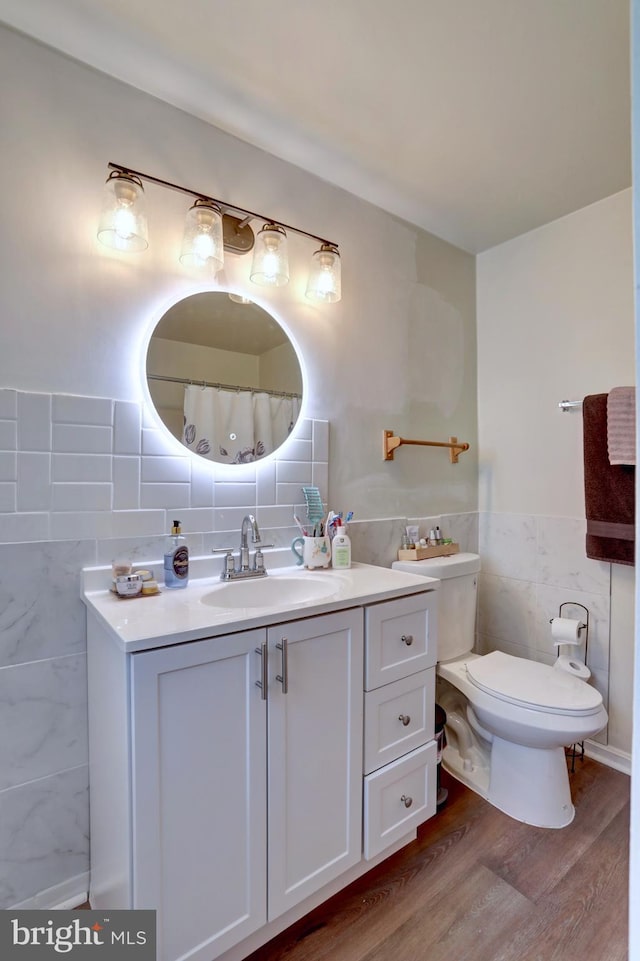 bathroom featuring wood-type flooring, tasteful backsplash, vanity, tile walls, and toilet