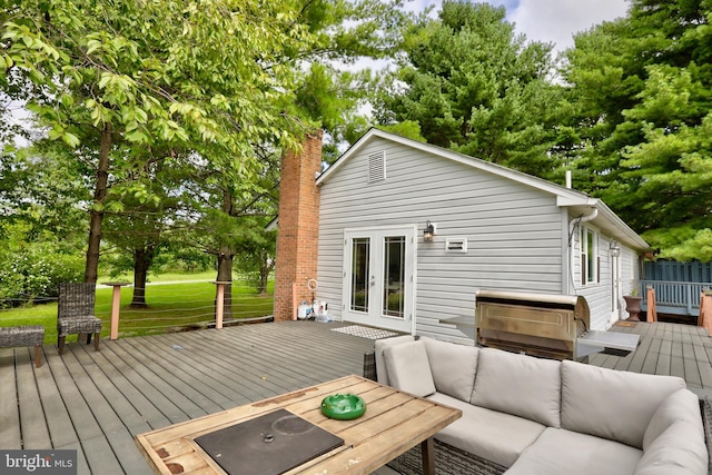 exterior space with a wooden deck, a lawn, outdoor lounge area, and french doors