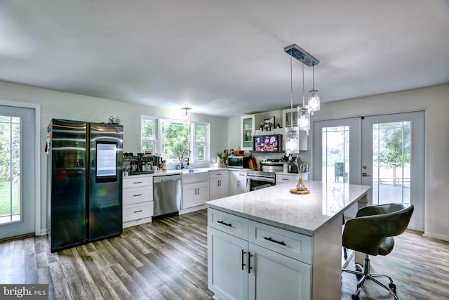 kitchen with appliances with stainless steel finishes, plenty of natural light, a breakfast bar, and wood-type flooring