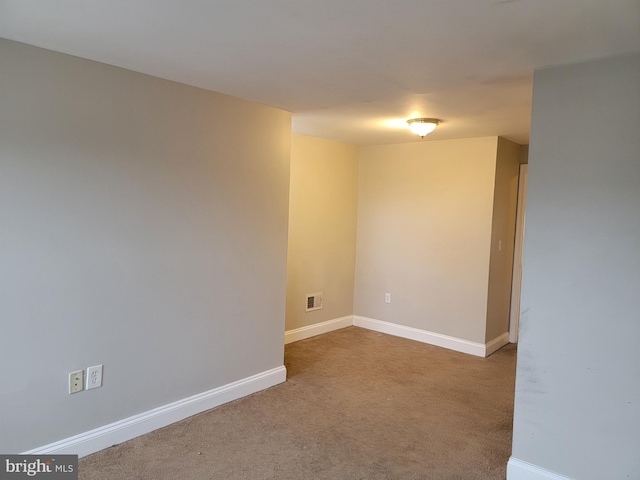 carpeted spare room featuring baseboards and visible vents