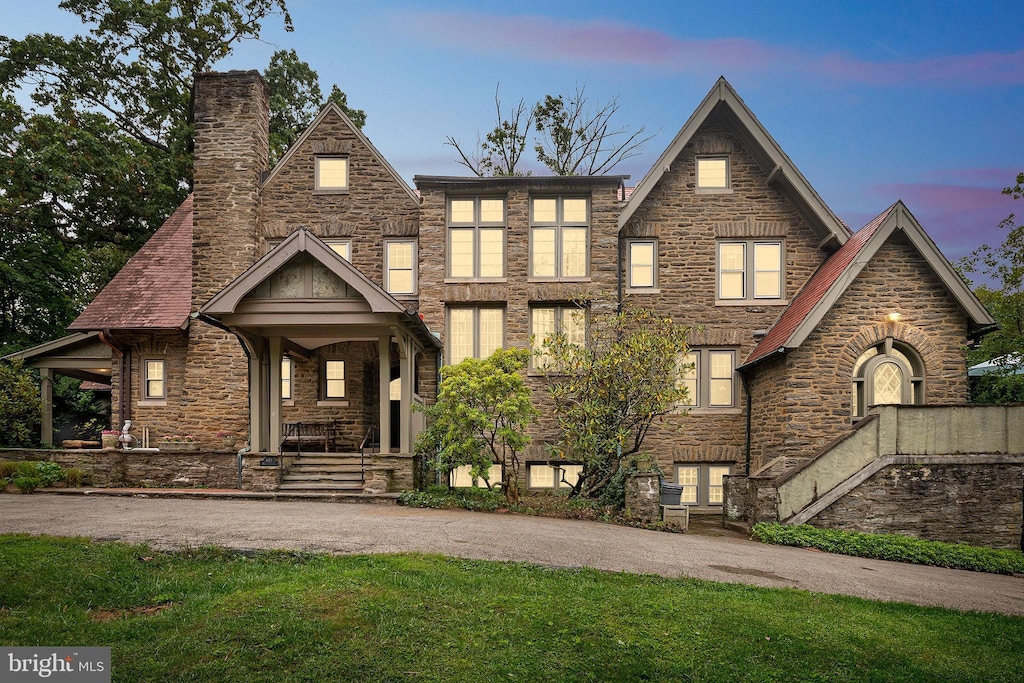 view of front of property with stone siding, a chimney, and driveway