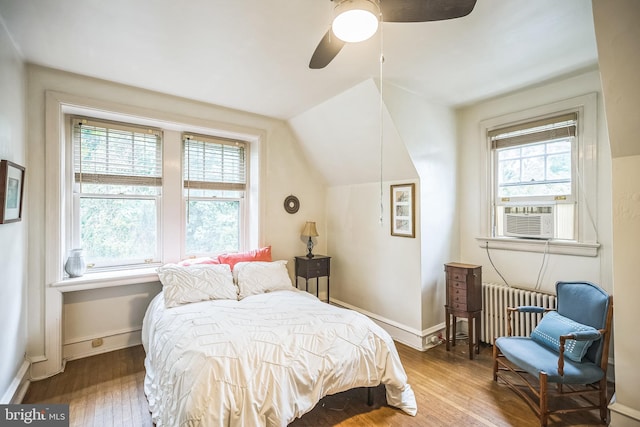 bedroom featuring cooling unit, vaulted ceiling, wood-type flooring, ceiling fan, and radiator