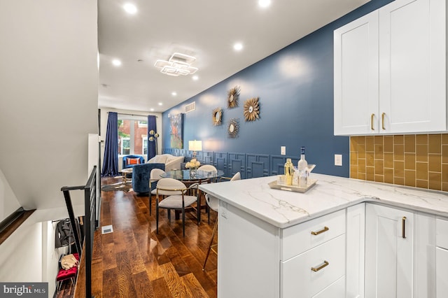 kitchen featuring white cabinetry, backsplash, light stone counters, and dark hardwood / wood-style flooring