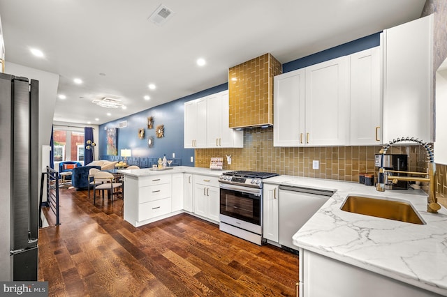 kitchen featuring backsplash, dark hardwood / wood-style flooring, light stone counters, stainless steel gas range, and white cabinetry