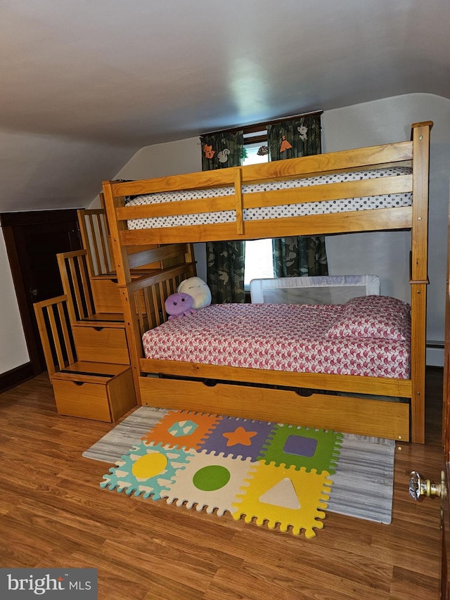 bedroom featuring wood-type flooring, vaulted ceiling, and a baseboard heating unit