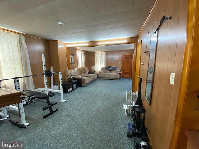 workout room with wood walls, carpet floors, and radiator heating unit