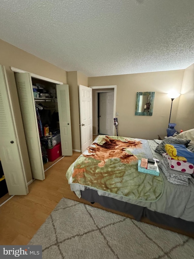 bedroom with hardwood / wood-style floors, a closet, and a textured ceiling