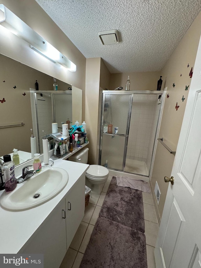 bathroom with a textured ceiling, vanity, an enclosed shower, tile patterned flooring, and toilet