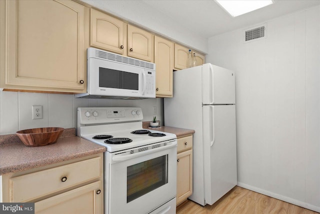 kitchen with light brown cabinetry, light hardwood / wood-style floors, and white appliances