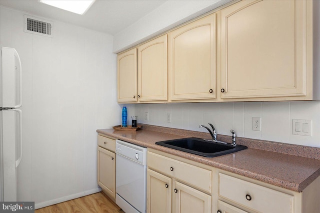 kitchen with light wood-type flooring, sink, cream cabinets, and white appliances