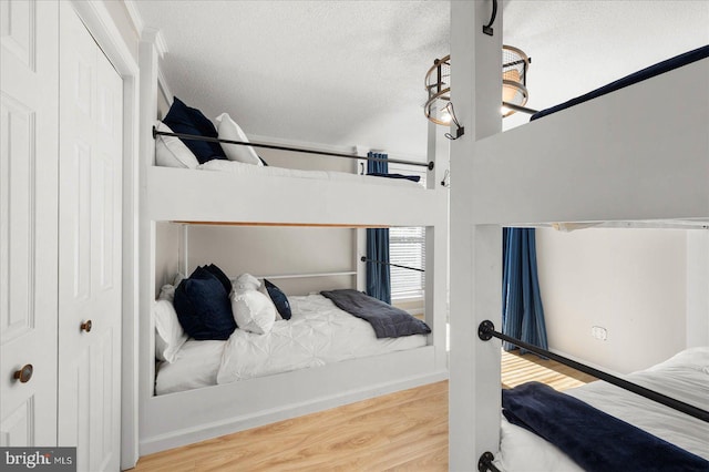 bedroom featuring light wood-type flooring, a closet, and a textured ceiling