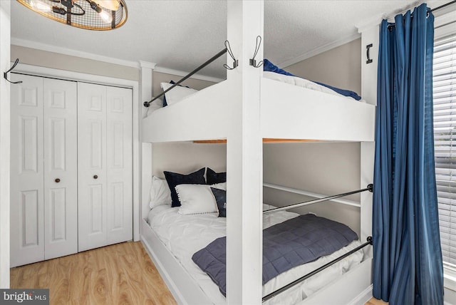 bedroom with a closet, crown molding, a textured ceiling, and light hardwood / wood-style floors