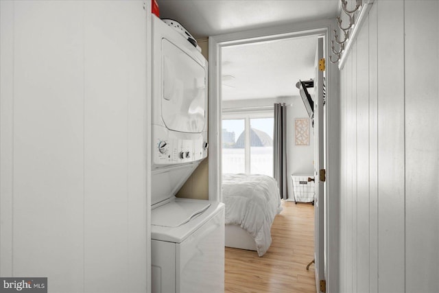 clothes washing area with stacked washer and dryer and light wood-type flooring