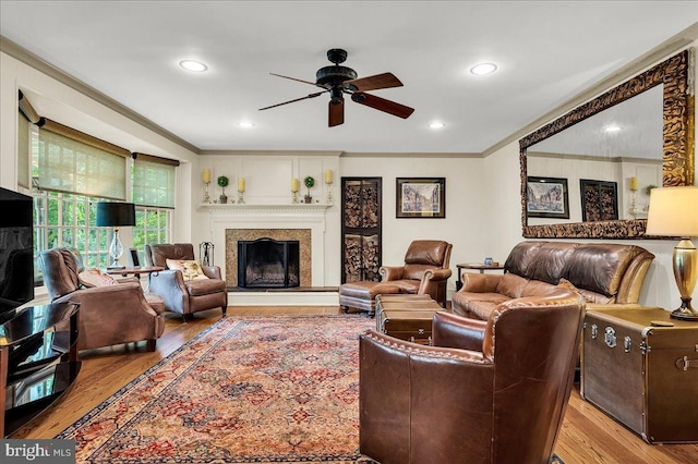 living room featuring light wood finished floors, ceiling fan, ornamental molding, a fireplace, and recessed lighting