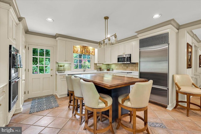 kitchen featuring stainless steel appliances, a center island, decorative backsplash, decorative light fixtures, and crown molding