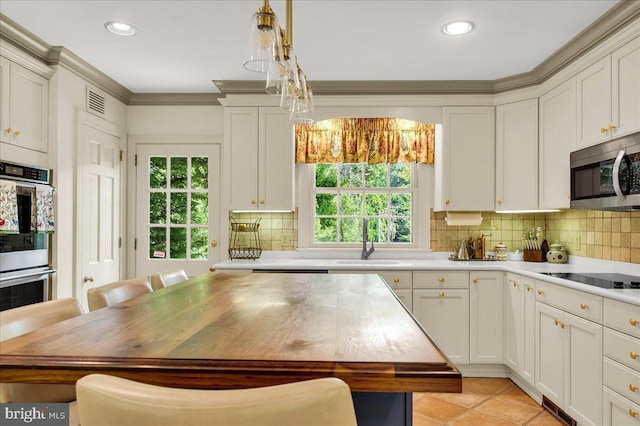 kitchen with pendant lighting, stainless steel appliances, light countertops, backsplash, and a sink