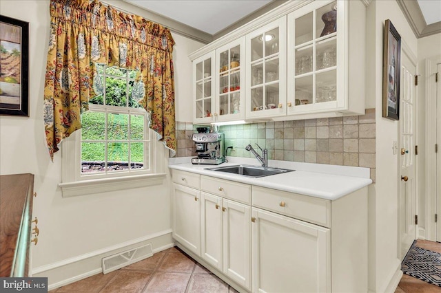 kitchen with visible vents, glass insert cabinets, light countertops, white cabinetry, and a sink