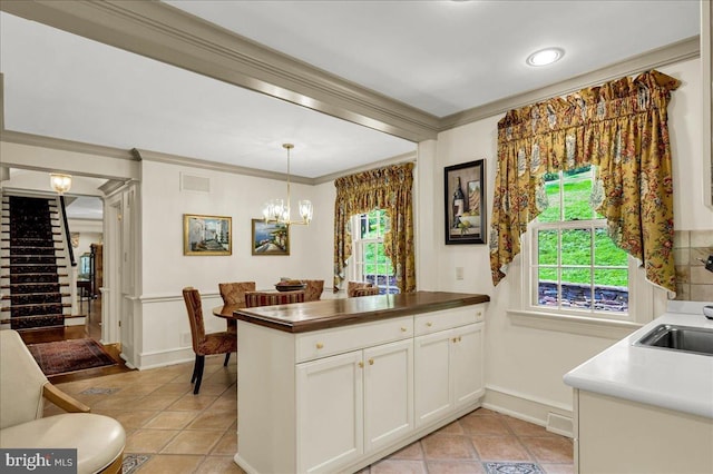 kitchen with visible vents, a healthy amount of sunlight, white cabinetry, ornamental molding, and pendant lighting