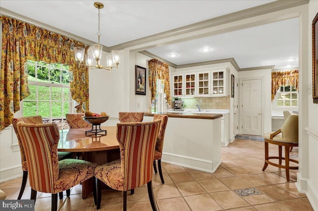 dining area with light tile patterned floors, a chandelier, and crown molding