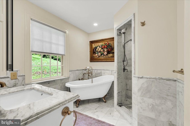 bathroom featuring marble finish floor, a marble finish shower, wainscoting, vanity, and a freestanding tub