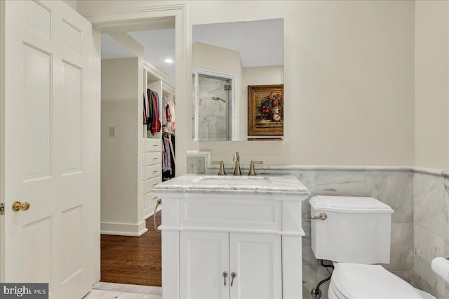 bathroom featuring a wainscoted wall, tile walls, toilet, vanity, and wood finished floors