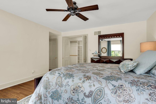 bedroom with a ceiling fan, visible vents, baseboards, and wood finished floors