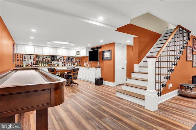 recreation room with light wood finished floors, baseboards, indoor bar, and recessed lighting