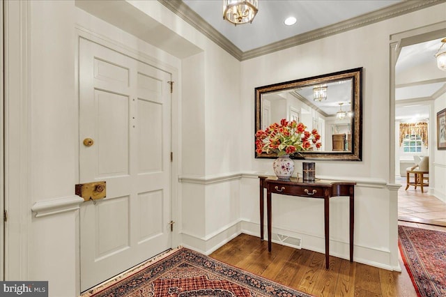 foyer entrance featuring recessed lighting, crown molding, dark wood-type flooring, visible vents, and an inviting chandelier