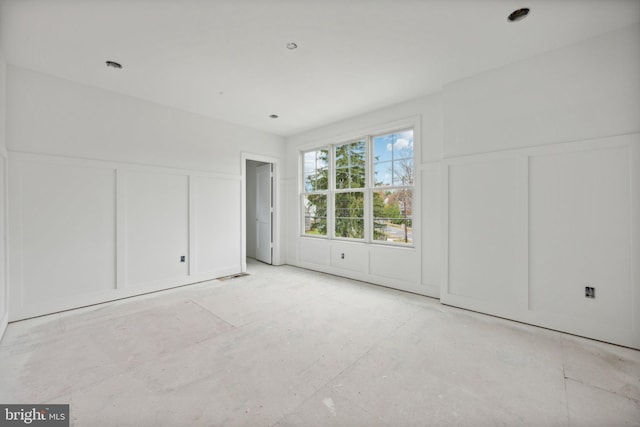 unfurnished bedroom with a decorative wall and wainscoting